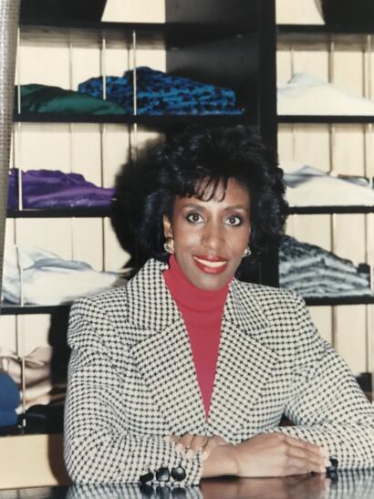 Iris poses in front of shelves of merchandise in an minimalist store setting