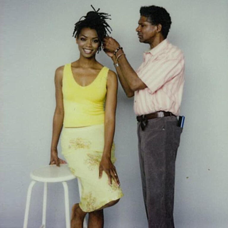 Buster Berkley fixing model's hair wearing yellow outfit.