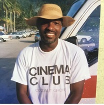 Man wearing a wide-brimmed hat and a "Cinema Club" T-shirt outdoors