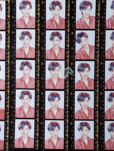 Strip of contact sheet featuring 20 color portraits of a woman with short, stylish hair, wearing a red top.