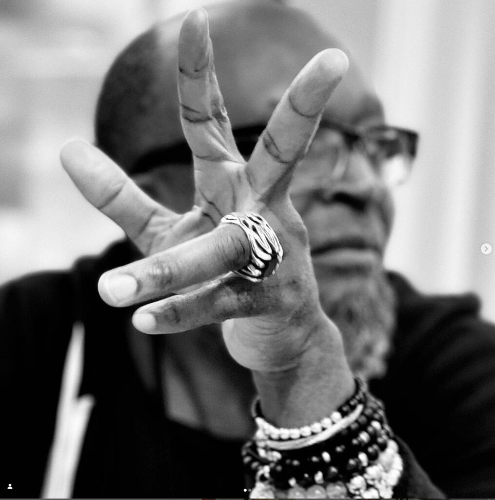 Close-up of a person wearing rings and bracelets, making a peace sign with fingers.