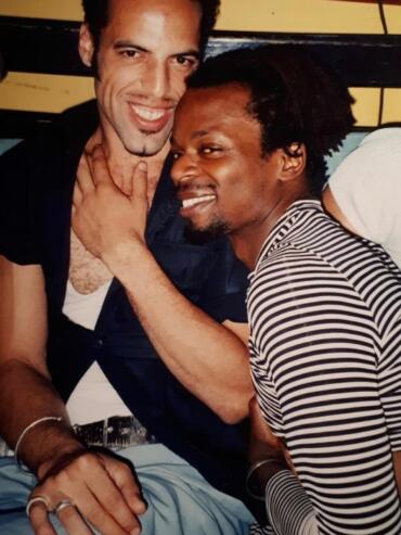 Two men enjoying a joyful moment together, smiling and embracing in a casual setting.
