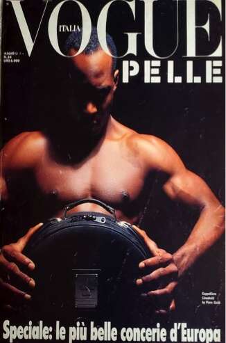 Vogue Italia cover featuring a muscular male model holding a camera, emphasizing strength and style.