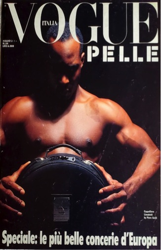 Vogue Italia cover featuring a muscular male model holding a camera, emphasizing strength and style.
