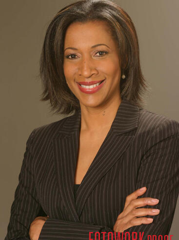 Confident woman in a professional pinstripe blazer smiling at the camera.