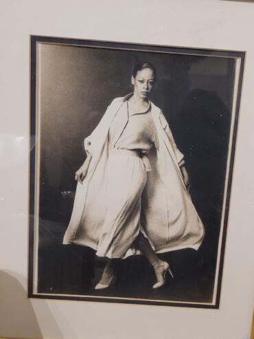 Black-and-white portrait of a woman in stylish, flowing clothing and high heels.