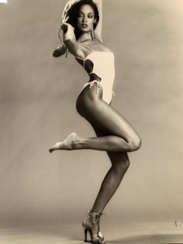Denise in an athletic pose wearing a white bathing suit.