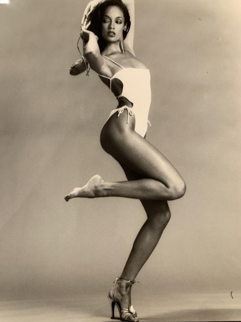 Denise in an athletic pose wearing a white bathing suit.