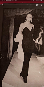 Woman in elegant black gown walking on runway.