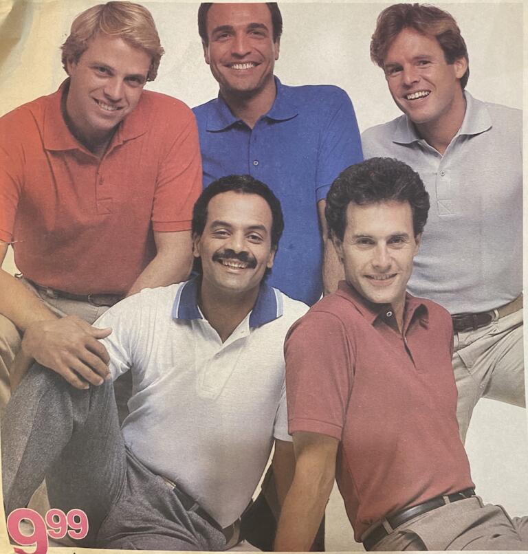 Group portrait of five men dressed in colorful casual shirts, smiling confidently.