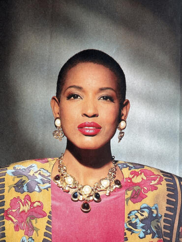 Elegant woman with a bold statement necklace and floral patterned blazer.
