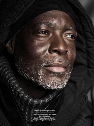 Close-up of a mature man in cold-weather gear with frost on his beard and a pensive expression.
