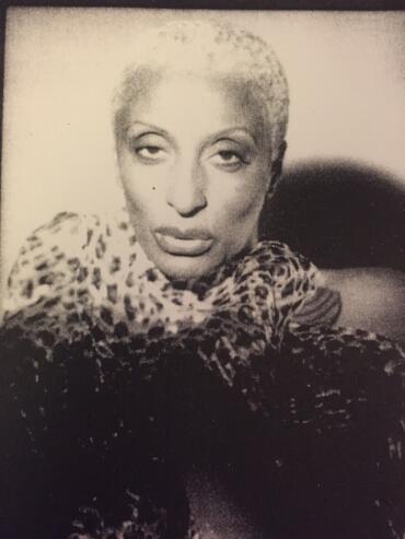 Black-and-white portrait of a woman with short, textured hair wearing a patterned scarf.