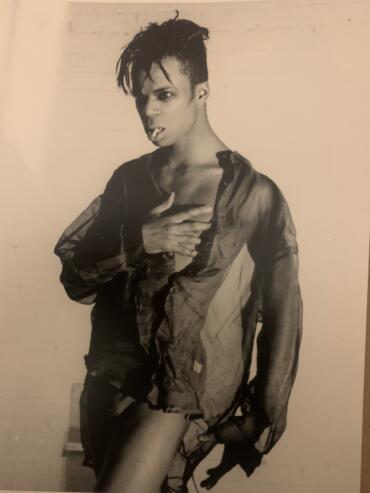 Black and white image of a young person with a textured, oversized jacket, striking a bold pose.