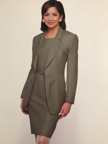 Woman wearing a plaid business suit, smiling against a neutral background.