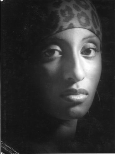 Portrait of a woman wearing a headscarf, captured in a black-and-white photography style.