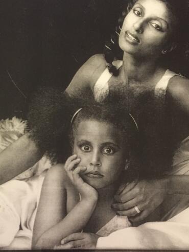 Black and white portrait of two women, with one resting her head on her hand and the other looking directly at the camera.