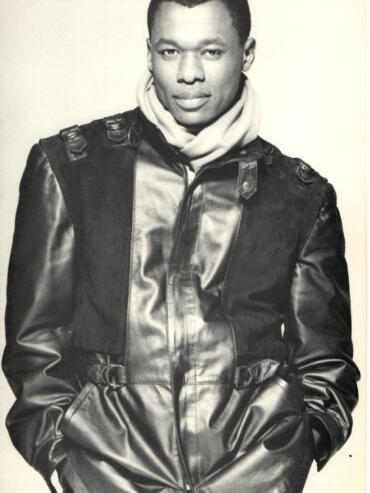 Male model in a leather jacket, layered with a light hoodie, in a monochrome fashion shot.