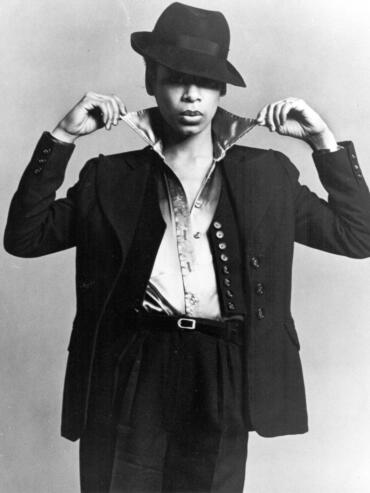 Black and white fashion photograph of a woman in an oversized blazer, silk shirt, and a wide-brim hat.