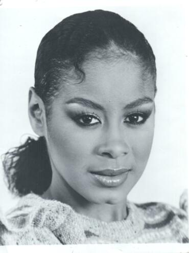 Black and white portrait of a woman with neatly styled hair, wearing a cozy sweater.