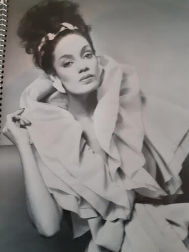 Black-and-white portrait of a woman with styled hair, earrings, and fashionable clothing.