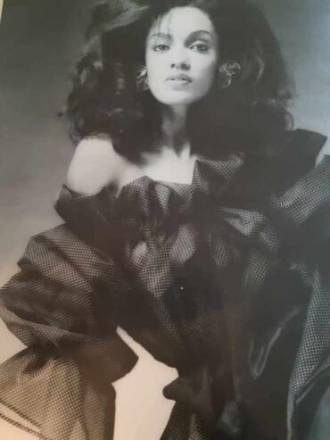 Black-and-white portrait of a woman with voluminous hair and elegant attire.