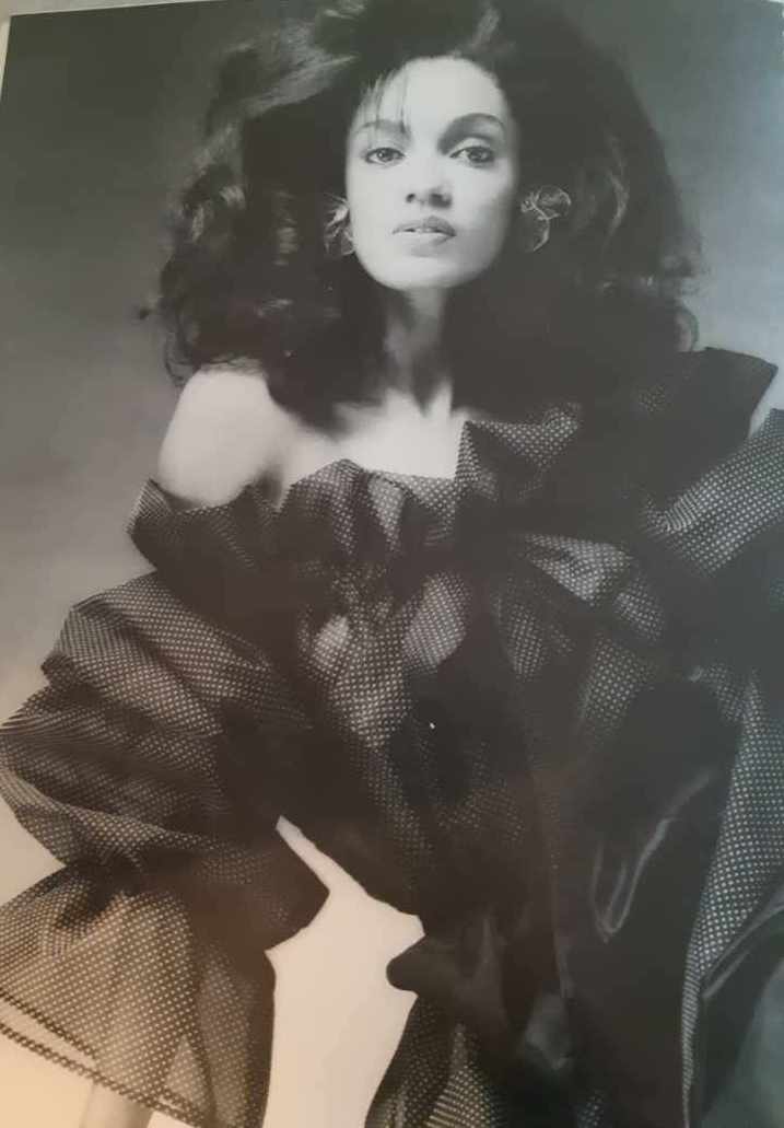 Black-and-white portrait of a woman with voluminous hair and elegant attire.