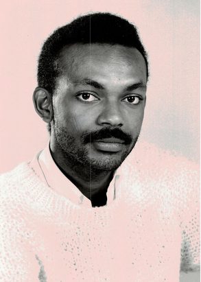 Black and white portrait of a young man with a textured sweater, looking at the camera.