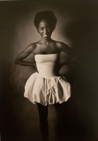 Fashion-forward woman in strapless dress with a voluminous skirt, smiling confidently.