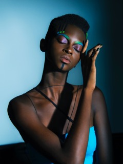 Stylish woman with colorful eye makeup and sheer black attire in a modern fashion shoot.