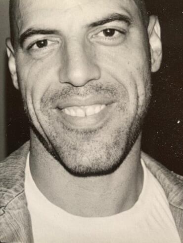 Close-up black and white portrait of a man with a friendly smile, casual style.