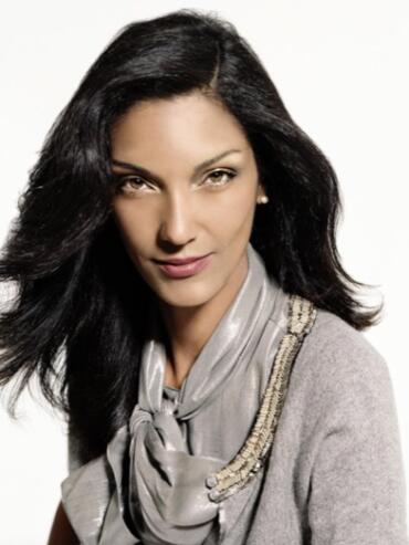 Elegant woman with dark, wavy hair wearing a silk scarf and a gray top.