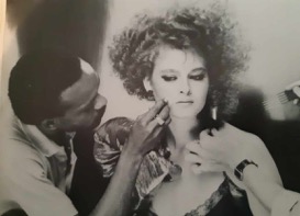A woman gets makeup applied by a stylist in a professional setting.