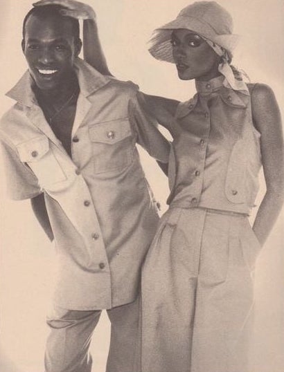 Black and white photo of Denise McLeod standing beside Calvin French, the two Black supermodels of their time, their arms around each other, both wearing vintage House of Lorraine fashions, 1976