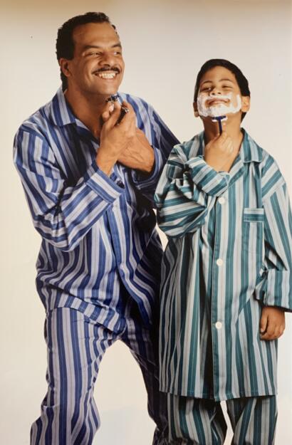 Father and son in matching striped pajamas, enjoying a playful moment with shaving foam.