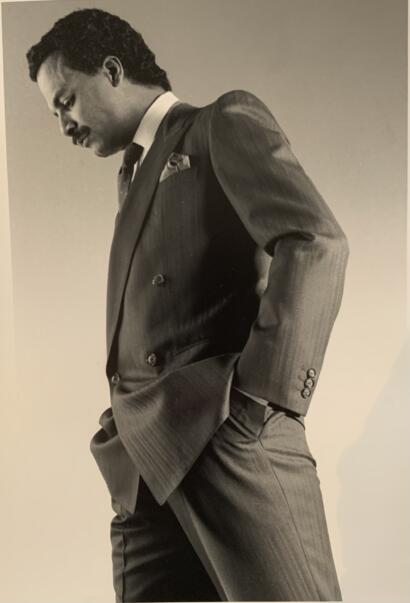 Black-and-white portrait of a man in a tailored suit, with a classic, sophisticated style.