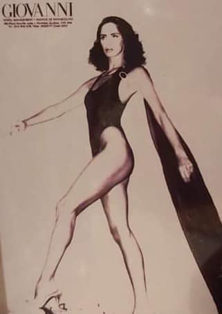 Fashion illustration of a woman in a black swimsuit and flowing cape, with a vintage vibe.