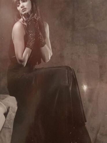 Vintage-inspired woman in a black dress, dotted gloves, and statement earrings.