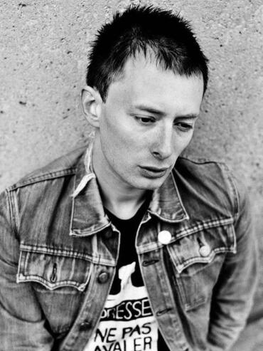 Black-and-white portrait of a man with short, spiked hair wearing a denim jacket.