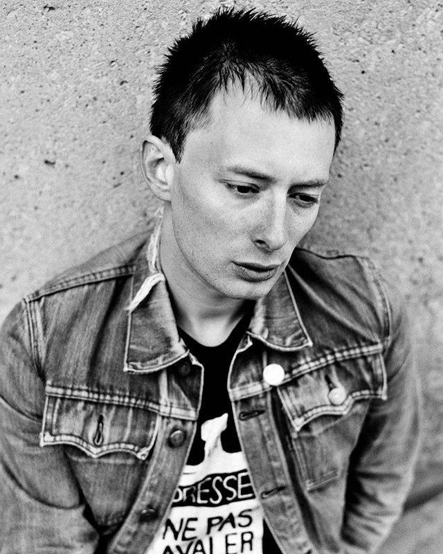 Black-and-white portrait of a man with short, spiked hair wearing a denim jacket.