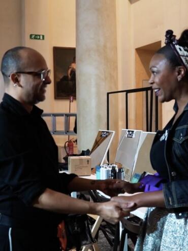 Two women share a handshake and friendly conversation at a networking event.