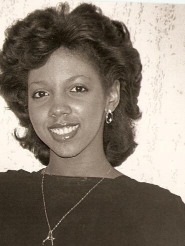 Elegant woman with styled hair, hoop earrings, and a cross necklace.
