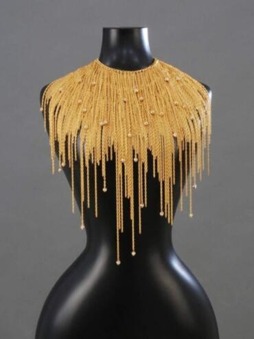 Golden beaded fringe necklace drapes elegantly over a black mannequin bust.