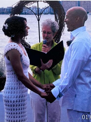 Couple exchanging vows at an outdoor waterfront wedding ceremony.