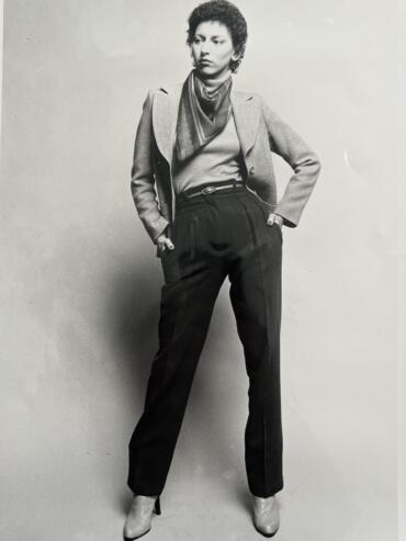 Vintage black-and-white photo of a woman in high-waisted pants, blazer, and scarf.