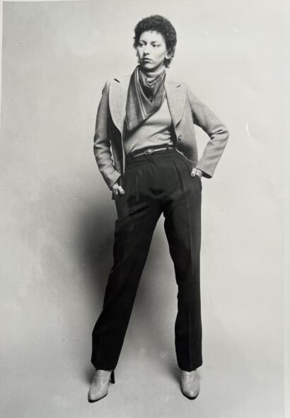 Vintage black-and-white photo of a woman in high-waisted pants, blazer, and scarf.