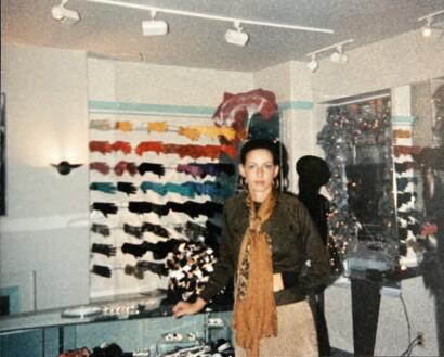 A stylish woman in a fashion boutique with colorful accessories and display shelves.