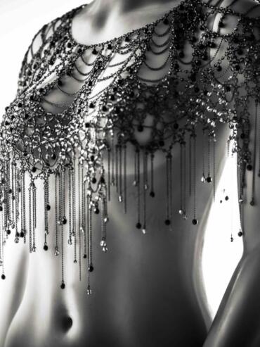 Close-up of a mannequin wearing an intricate black beaded shoulder and chest adornment.