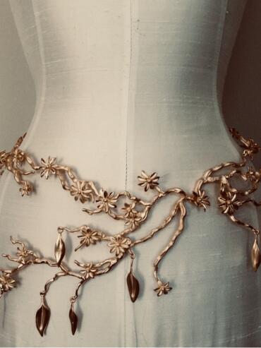 Elegant gold floral necklace displayed on a white fashion dress.