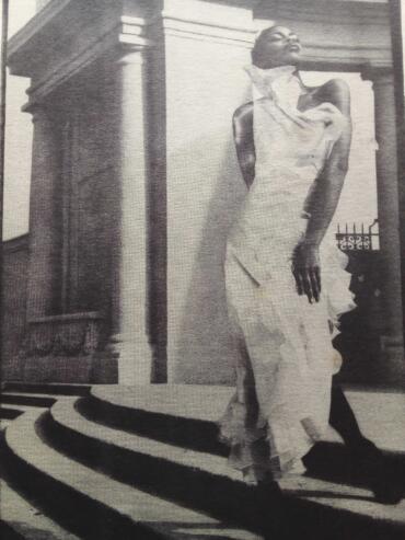 Statue of a woman in a long dress standing at a building entrance on black and white striped steps.